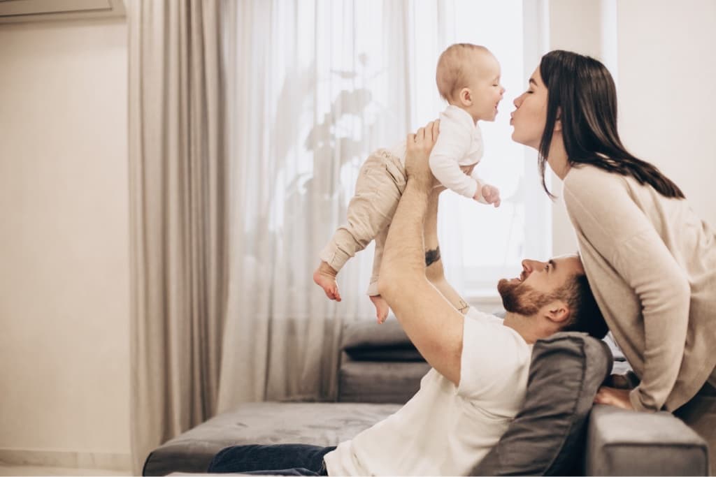 A mom and her partner playing with their baby at home